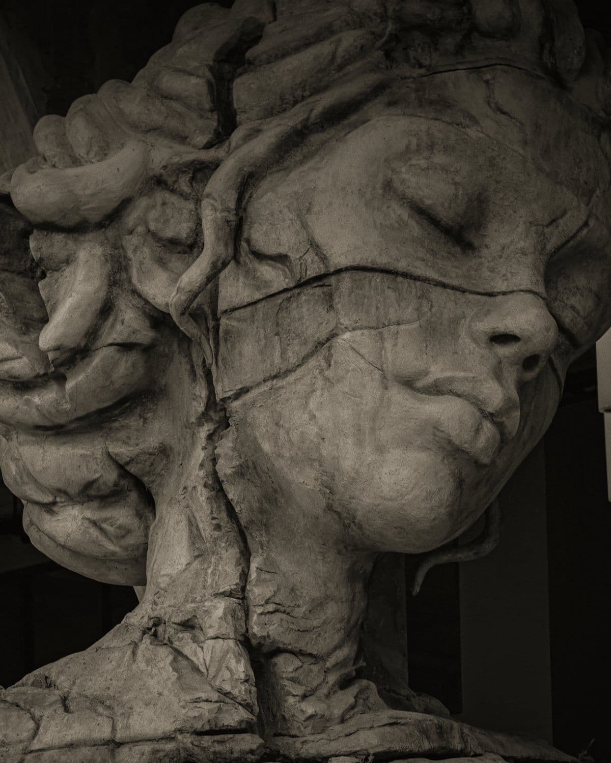 Head of a carved stone figure, eyes closed, turned into shadow